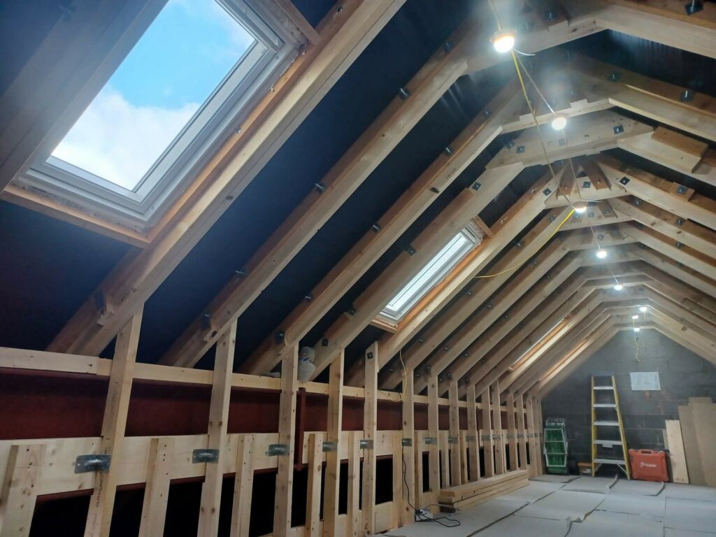 joinery in an attic that's in progress with velux windows showing blue sky